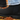 Close-up of a person wearing cuffed light-blue jeans and a black Chelsea boot, standing on wet autumn leaves.