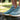 Person wearing green 8000Kicks sneakers balancing on a stone ledge outdoors, highlighting the wide toe box and cushioned sole.