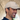 Bernardo, CEO and co-founder of 8000kicks, wearing a beige cap from his brand, smiling inside a hallway.