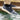 Dark navy hemp sneakers with a cream midsole and gum outsole, one foot splashing through water at the edge of a tiled pool.