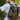 Person wearing a green 8000Kicks Nomad hemp backpack while taking a photo outdoors near a camper van, showcasing the backpack's roll-top design and spacious travel-friendly capacity.