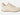 A single low-top sneaker in off-white canvas with matching laces, a small orange pull tab, and a brown outsole, shown from the side on a light gray background.