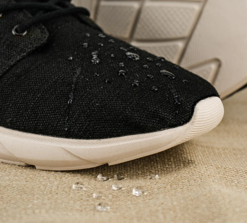 A pair of black and white hemp shoes with water droplets.